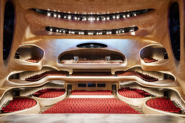 Harbin Opera House, China by MAD. The smooth, sinuous surfaces of the exterior continue inside. A large block of Manchurian Ash wood has been designed to appear as though it is gently eroding away.