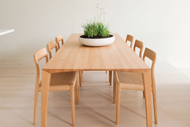 A light oak dining table completes the pared-back aesthetic of the kitchen area.