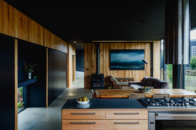 Black ceilings and cabinetry lend contrast and definition to the raw-material palette of timbers and untreated metals in the kitchen.