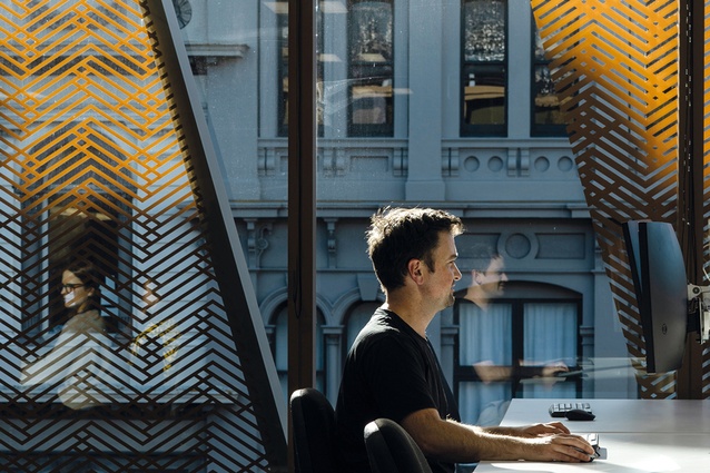 A layered composition of golden aluminium fins, paired with the woven frit pattern, creates a dynamic interplay between contemporary detailing and the surrounding heritage fabric.