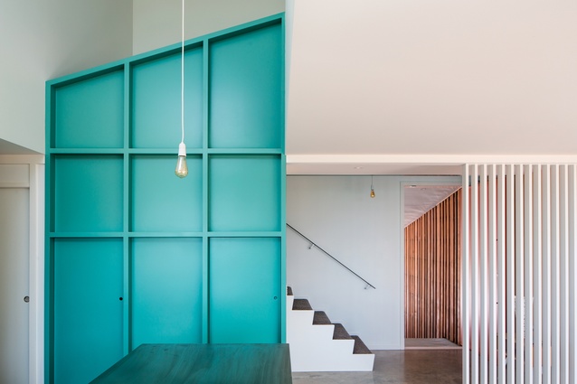 The staircase wraps upwards and is a simple, relatively cost-effective architectural element. The kitchen pantry has exposed framing to form the balustrade.
