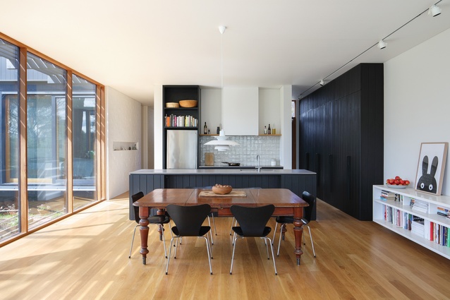 Kitchen joinery is in the same dark cladding as the external walls, while large windows capture views of the bush.