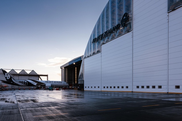 Apron-side perspective at dawn. The hangar’s translucent cladding hints at the timber structured volume within.