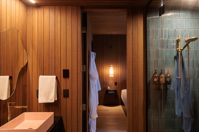 Bathrooms feature black oak cabinetry, hammered granite tops, GRC basins, Abodo timber walls and ceilings, and showers dressed in blue-green finger tiles.