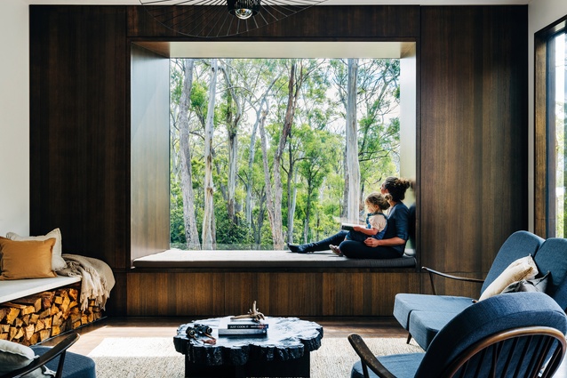 A large window in the living space frames the vista of surrounding bushland.