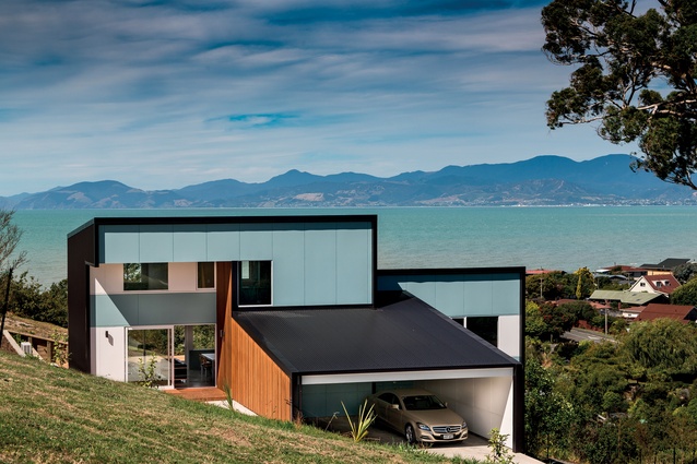This elevation faces the hillside and captures the colour of the ocean. The carport roof is the bracing element, with steel in behind the timber framing. 