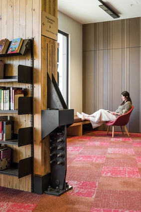 Detail of a CLT rocking wall foregrounds a quiet nook in the library.