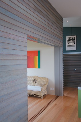A corner of the morning room, with the corridor leading to the entrance, laundry and stairs beyond. The exterior cedar cladding has been brought inside.