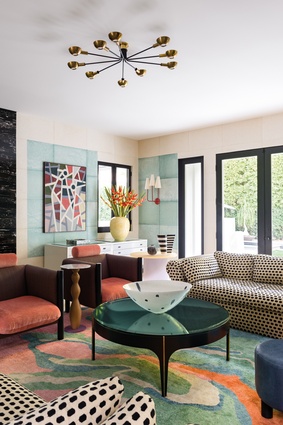 The living room mixes contemporary and vintage as well as a variety of hues and patterns to create a highly eclectic and vibrant space. The furniture includes: a Stilnovo chandelier, vintage sofas, and pieces custom-designed by both Kelly Wearstler and home-owner Lana Gomez.