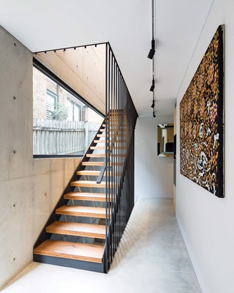 The black steel staircase “glints and glistens” when it catches the light coming through the large picture window. Artwork: Johnny Warangkula Tjupurrula.