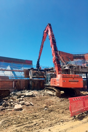 The long-reach excavator makes light work of the demolition process. 
