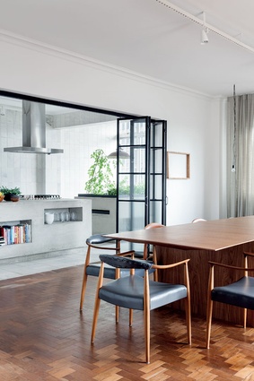 The elegant line of the furniture and the warmth of wood are contrasted with a Modernist materiality of concrete, steel and glass in the kitchen.