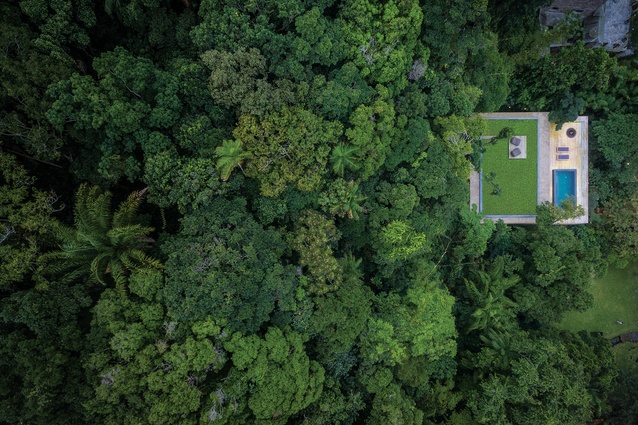 Created mostly from concrete and timber, the house features a green roof that blends into the trees when seen from above.