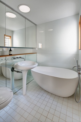 The white palette, mirrors and curved bathroomware help the small bathroom to feel more spacious than it is.