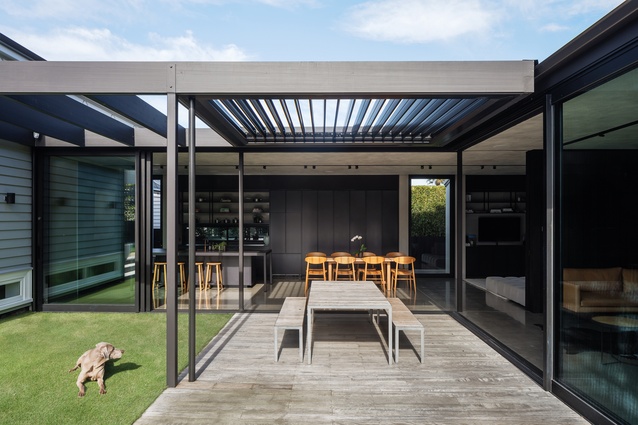 A cantilevered arm of the living pavilion stretches right over the outdoor seating area; its louvred roof and sliding screen doors blur the line completely between indoor and outdoor. 