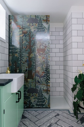 In the bathroom, a fantastical forest scene unfolds on the shower screen, against the same brick-patterned wallpaper that wraps the rest of the apartment.