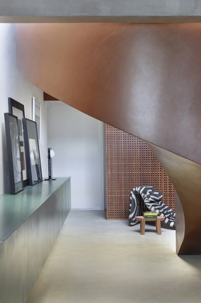 “The sinuous semicircular staircase... is a strong sculptural piece, its curving form accentuating its metallic finish as it connects to the first floor.”