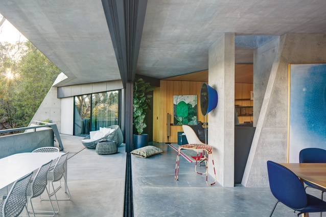 The living areas of the residence are arranged on the upper level, where a wide concrete eave shades an expansive balcony. Artwork: Sally Ross.