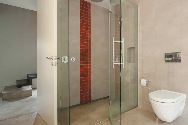 The sandy colours in the ensuite bathroom are offset by a vertical splash of rich-red tiles in the shower. 