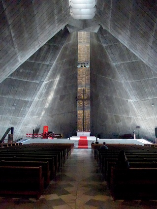 The dim interior of the Church of St Mary, a soaring Catholic cathedral designed by Kenzo Tange in 1964, with its low, heavy hyperbolic ceiling sweeping up above the altar to a concrete crescendo.
