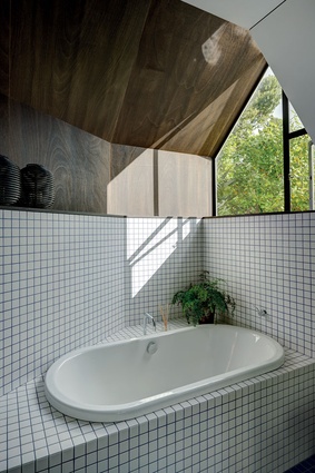 The bath sits in the window plinth below a telescopic window, which draws light through the room.