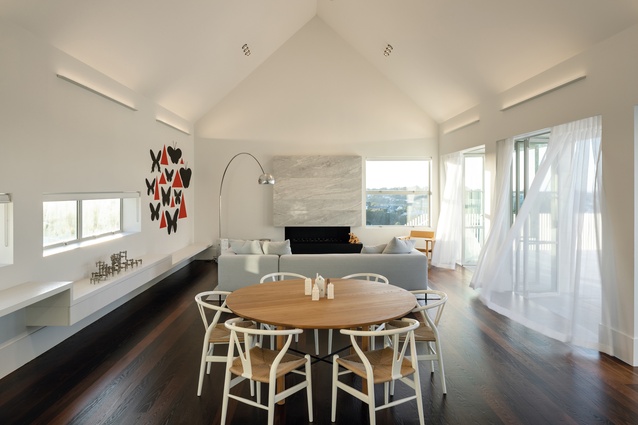 An informal dining table and sofa by <a 
href="https://simonjames.co.nz/"style="color:#3386FF"target="_blank"><u>Simon James Design</u></a> are the heart of this light-filled living area. An artwork by Richard Kileen and a vintage Nagel candelabra add intrigue.