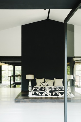 The master bedroom features a black wall with a bed on a simple wooden platform in a Japanese style. 