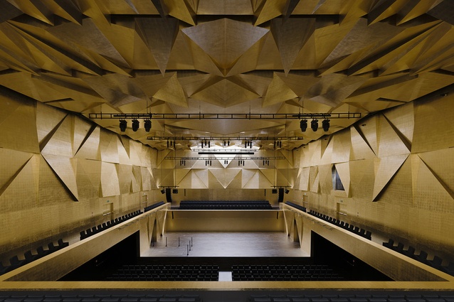 Szczecin Philharmonic Hall, Poland by Estudio Barozzi Veiga. The walls and ceiling of the stunning main symphony hall are textured with angled triangular panels covered in gold leaf.