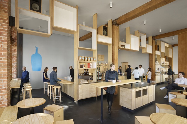 Blue Bottle cafe, South Park, San Francisco, 2017. A former warehouse has been transformed into a light-filled, minimal interior space featuring warm wood and pale blue walls.