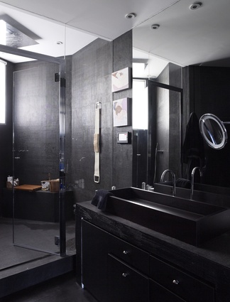 The dark-toned bathroom – in contrast with other rooms – features a custom-made sink and cabinet.