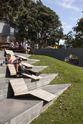 Bleachers with lounge furniture and interesting triangular insertion into mound of earth. 