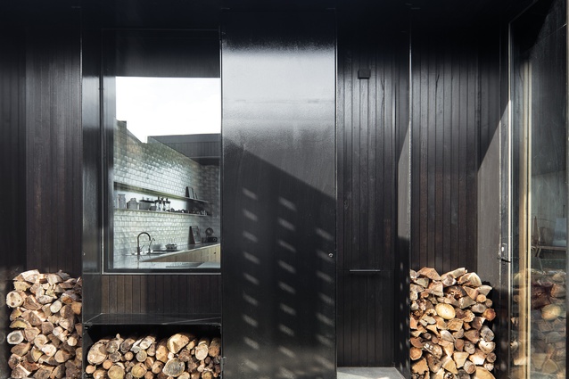 The entry courtyard is lined with crisp, black steelwork, which offsets the roughness of the recycled brick wall.