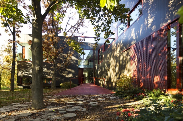 Moroso says the home’s cedarwood façade and deep-red accents were inspired by the colour of African soil, and the surrounding woodland in autumn.