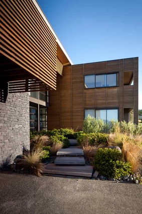 Stepped wooden decking leads to the front door through a rugged rock garden. 