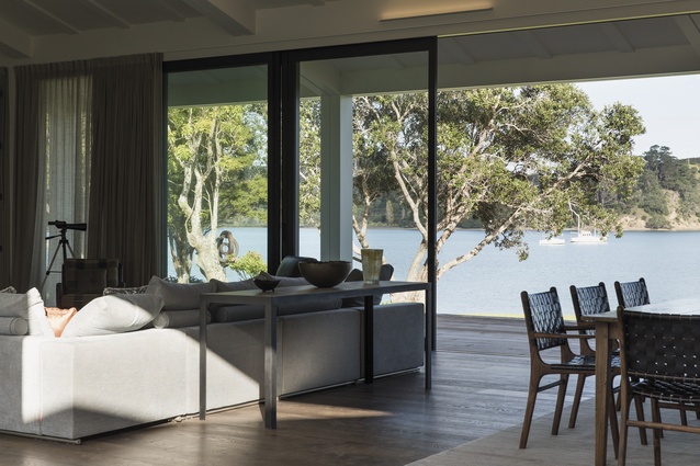 The communal areas of the house open through stacking sliding doors to decking that sits above the quiet bay, with its mature pohutukawa trees.