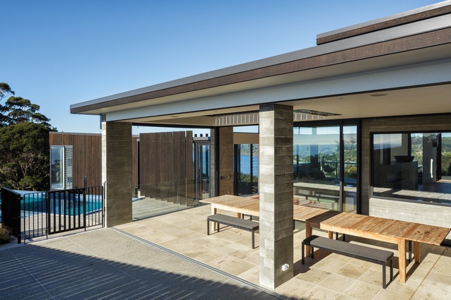 From the exterior courtyard, peaks of sea and rural views can be seen through the living area and past the pool.