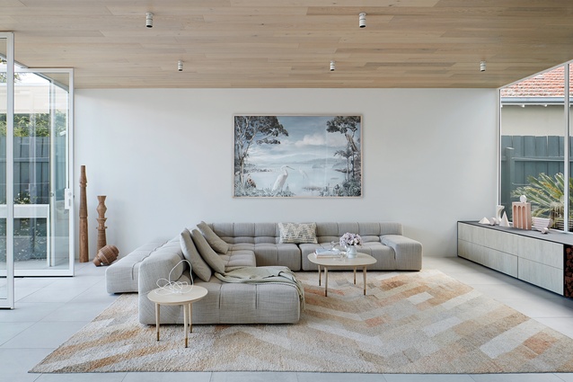 Nestled between the backyard and the courtyard, the white-hued volume of the central living room glows luminous with natural light. Artwork: Valerie Sparks.