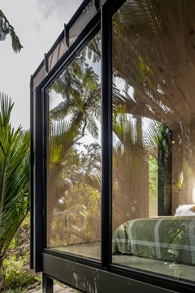 Large glazed windows in the hut's sleeping quarters provide expansive views out to the bush surroundings.