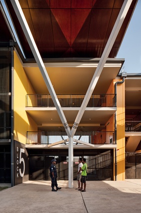 Triangular steel struts lift up the generous timber canopies, offering shade and shelter to the student rooms in the base of the building.