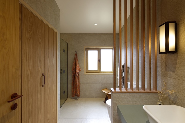 Textured tile creates a tranquil environment for bathroom rituals. Timber privacy screens are used throughout as a unifying design feature.