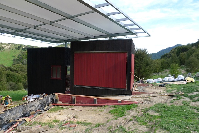 The drawbridge at the Welcome Shelter has been installed, along with the other distinctive red joinery that offsets the dark stained cedar cladding.