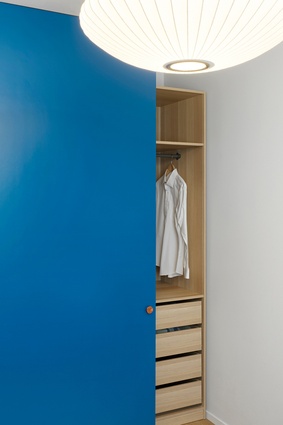 The home's timber palette is punctuated with a bold blue wardrobe door.