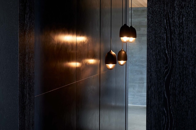 A waxed steel wall and bespoke glass pendants provide warmth and glow in the entrance hallway.