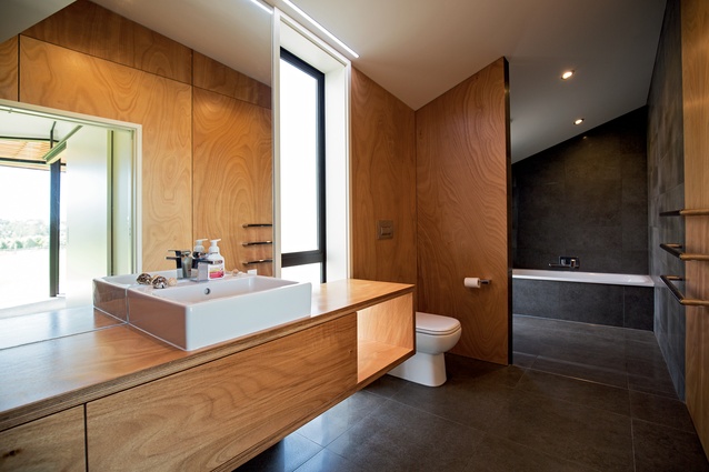 The bathroom features a large wet area combining the shower and bath. Gaboon plywood was also used extensively in this space.