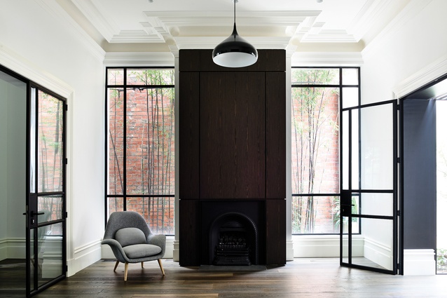 The existing fireplace is wrapped by dark veneer joinery panels, referencing proportions typical of late-nineteenth-century residential architecture.