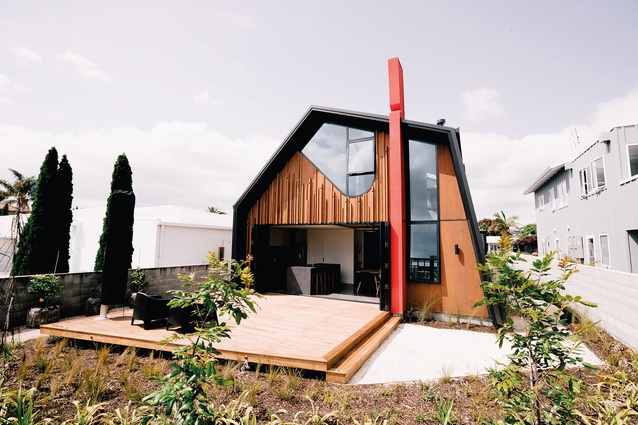 The courtyard or ‘front’ of the whare, facing e koro Mauao, includes a striking 12m-high red pouwhenua.
