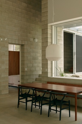 Doors and windows punctuate the block walls, fostering a free flow between interior and exterior spaces.