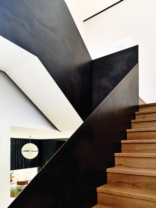 A sculptural black steel balustrade, sealed with black boot polish, lines the stair.