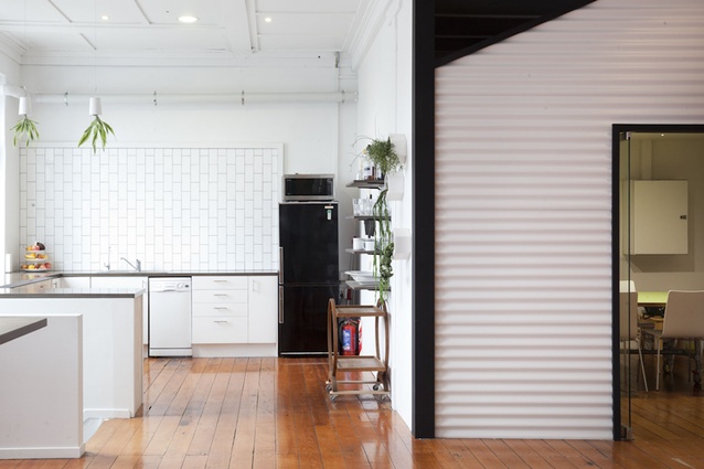 The white-tiled kitchen with polished yet well-trodden timber floors.