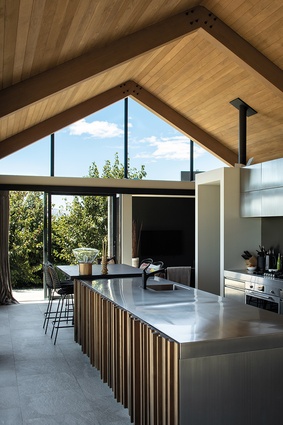The kitchen island is clad in cedar battens and topped with shining stainless steel.